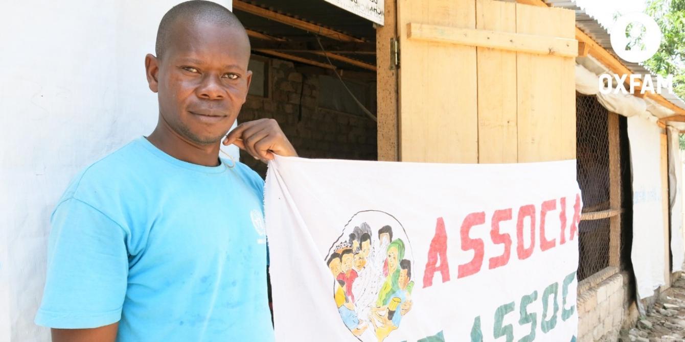 26 mars 2019-Azor NZAPAYEKE tient la banderole de son association ‘Les Associés de la paix’, dans le 5è arrondissement de Bangui. Il est le président de ce groupement d’élevage de poulets de chair, bénéficiaire du projet Oxfam 3X6. ©Aurélie GodetOxfam 26 mars 2019-Azor NZAPAYEKE tient la banderole de son association ‘Les Associés de la paix’, dans le 5è arrondissement de Bangui. Il est le président de ce groupement d’élevage de poulets de chair, bénéficiaire du projet Oxfam 3X6. ©Aurélie GodetOxfam
